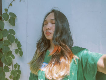 Portrait of young woman standing against wall