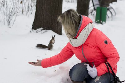 Woman feeding squirrel at park during winter