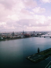 City at waterfront against cloudy sky