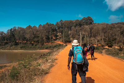 Rear view of a group of hikers on a dirt road against pine tree forest in makueni county, kenya