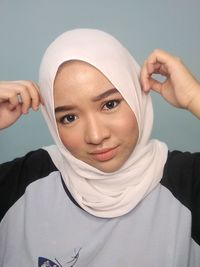 Close-up portrait of young woman wearing hijab against gray background