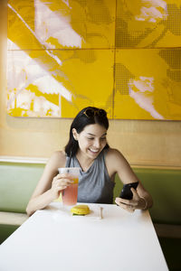 Portrait of young woman using mobile phone while sitting at home