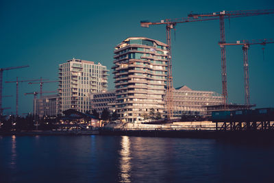 Buildings by river against sky in city