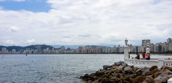 View of buildings by sea against sky