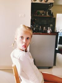 Portrait of cute girl sitting on chair at home