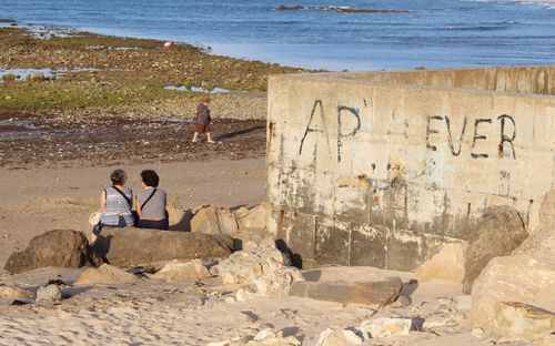 People sitting on beach by sea