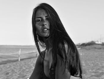 Portrait of smiling young woman on beach against sky