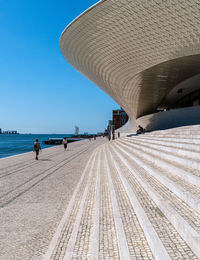 People at beach against clear blue sky