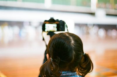 Rear view of girl photographing outdoors