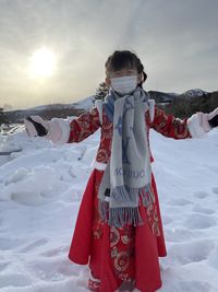 Girl standing on snow covered land against sky