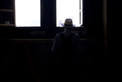 Rear view of man whit hat standing against window in istanbul
