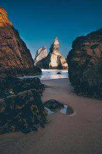 Scenic view of sea by mountains against clear sky