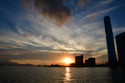 Scenic view of sea by buildings against sky during sunset