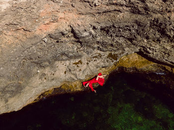 Woman swims in the sea in a red long dress with sunglasses in summer