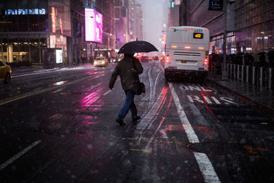 Man with umbrella walking on street during rainy season