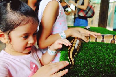 Close-up of cute smiling girl holding snake on green rug