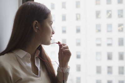 Young woman talking on smartphone through headphone