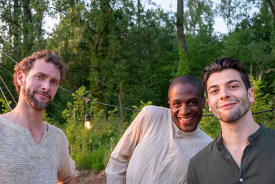 Portrait of smiling friends standing against trees