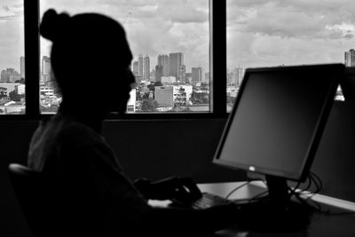 Rear view of man using laptop on table