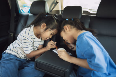 Siblings eating ice cream while sitting in car