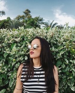 Portrait of young woman standing against plants