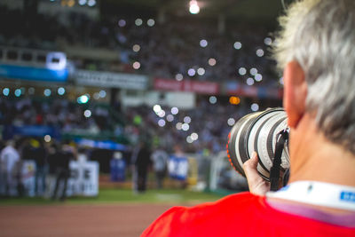 Cropped image of photographer standing with camera at stadium