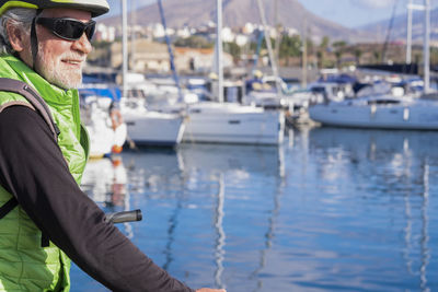 Side view of smiling senior man standing at harbor