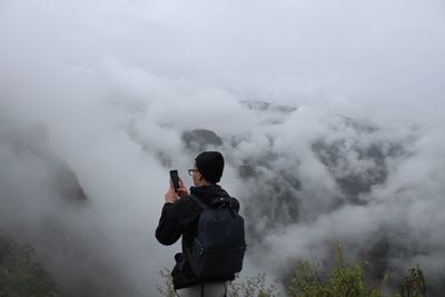Rear view of man photographing in foggy weather
