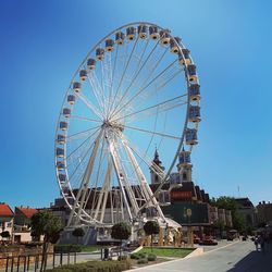 Ferris wheel in city against blue sky