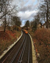 Railroad tracks amidst bare trees against sky