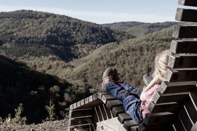 People sitting on bench against mountains