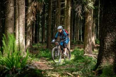 Young woman riding a mountain bike on footpath in the forest. salzburg, austria.