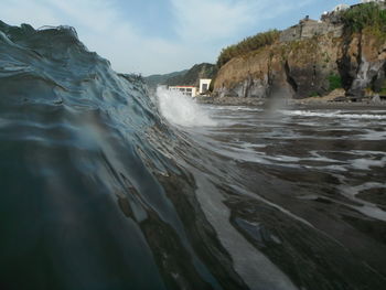 Scenic view of wave surf against cloudy sky