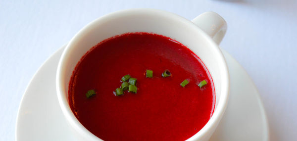 Close-up of red soup served in cup on table