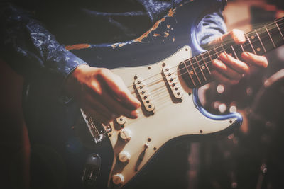 Midsection of man playing guitar