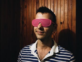 Young man wearing eyeglasses against wooden wall