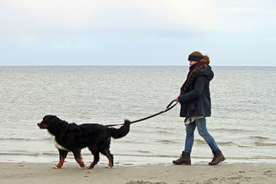 Full length of woman with dog walking on beach