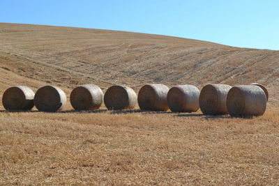 Hay bales on field against clear sky