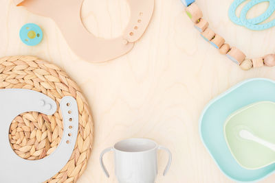 Baby accessories and tableware for food on wood. first feeding for kidst. top view dishware bib cup