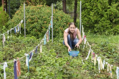 Portrait of smiling girl crouching by plants