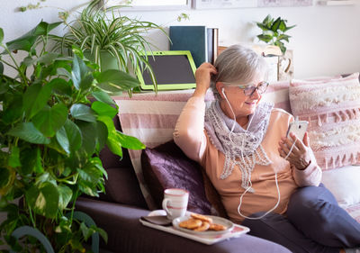 Midsection of woman using mobile phone while sitting on table