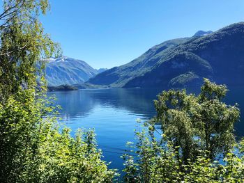 Scenic view of lake and mountains against clear blue sky