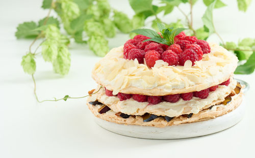 Round meringue pie with fresh raspberries on a white background, pavlova dessert