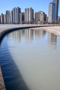 Reflection of buildings in city against clear sky