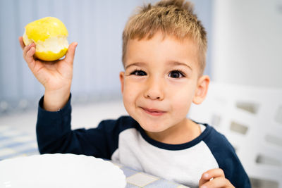 Portrait of boy holding ice cream on table