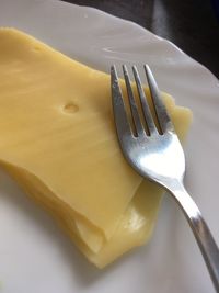 High angle view of cheese and fork in plate on table