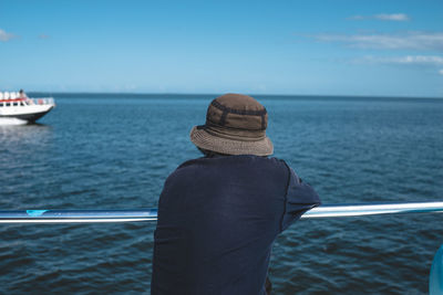 Rear view of man against sea and sky on sunny day