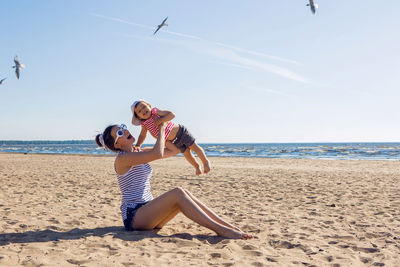 Mother and son sitting on the beach and flying around the birds seagulls