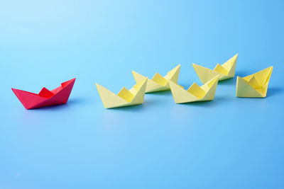 Multi colored paper boats against blue background