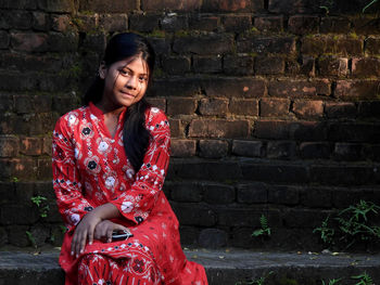 Portrait of woman standing against brick wall